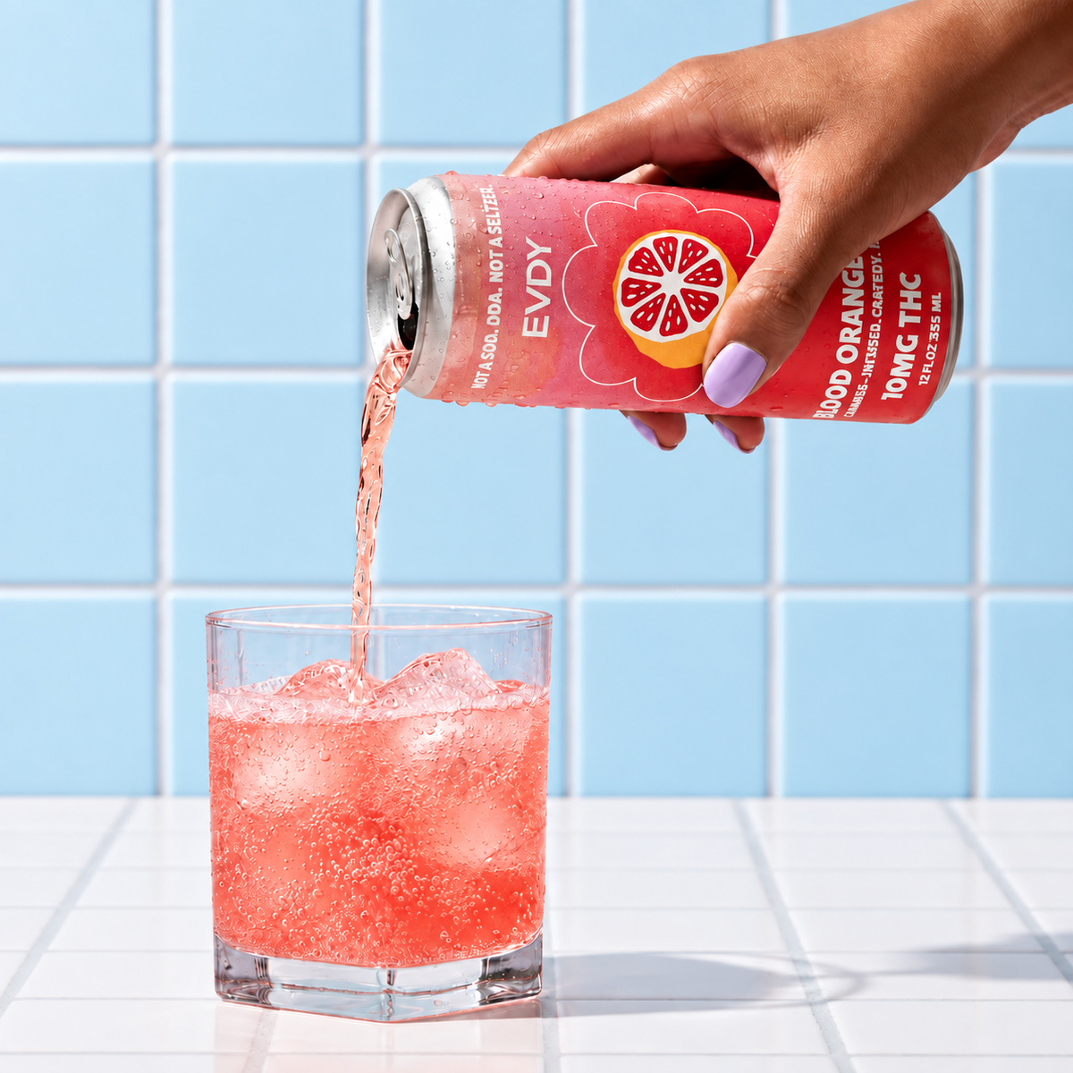 EVDY Blood Orange POM pouring over ice against a light blue tile background